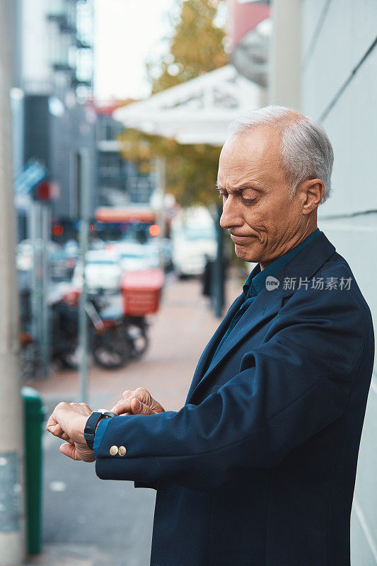 在城市街道上，一位成熟的商人皱着眉头看表