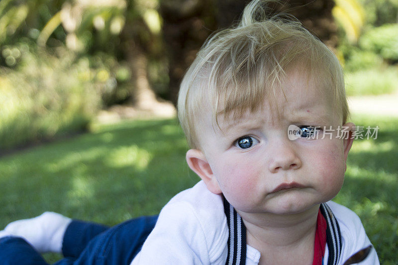 蓝眼睛的男婴躺在肚子上，抬头关注着镜头。