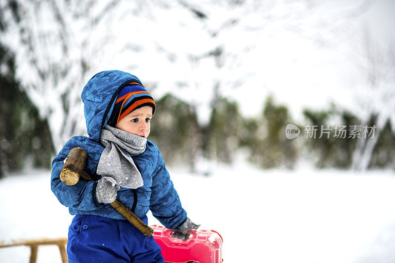 可爱的小男孩在大自然的雪地上修理雪橇