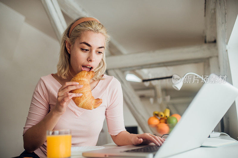 女人一边用笔记本电脑一边吃饭