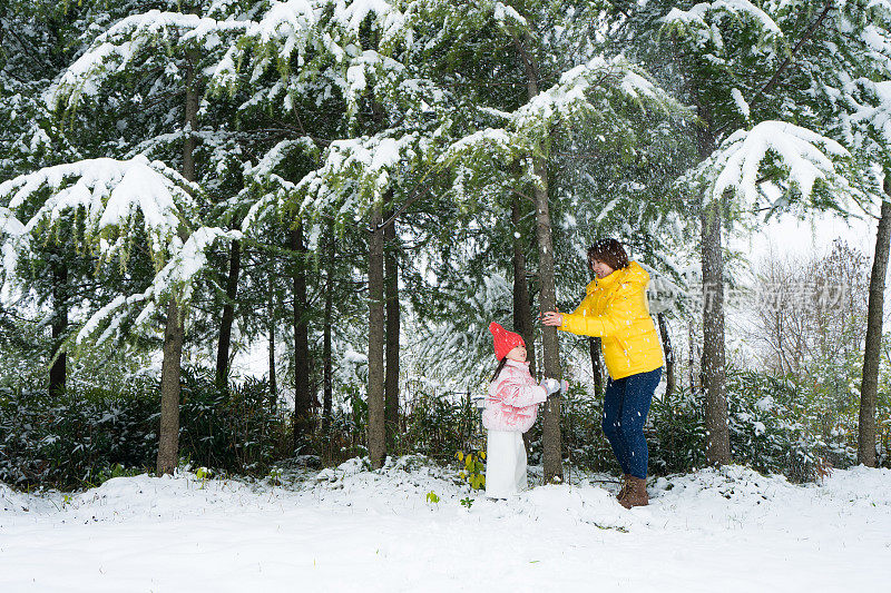 一个小女孩和妈妈在雪中玩耍