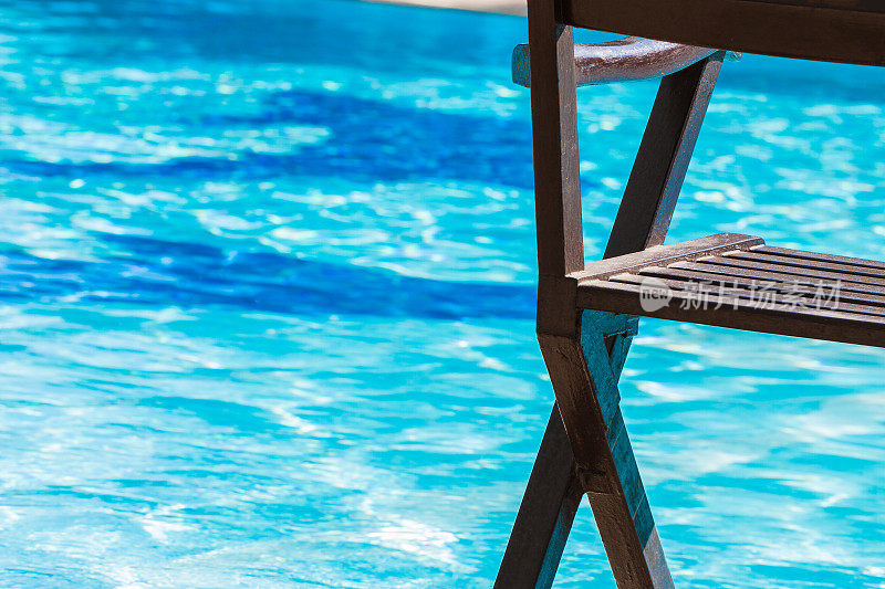 帆布躺椅，豪华游泳池，蓝色的海水，适合夏季旅游度假的海滩。放松的旅行概念