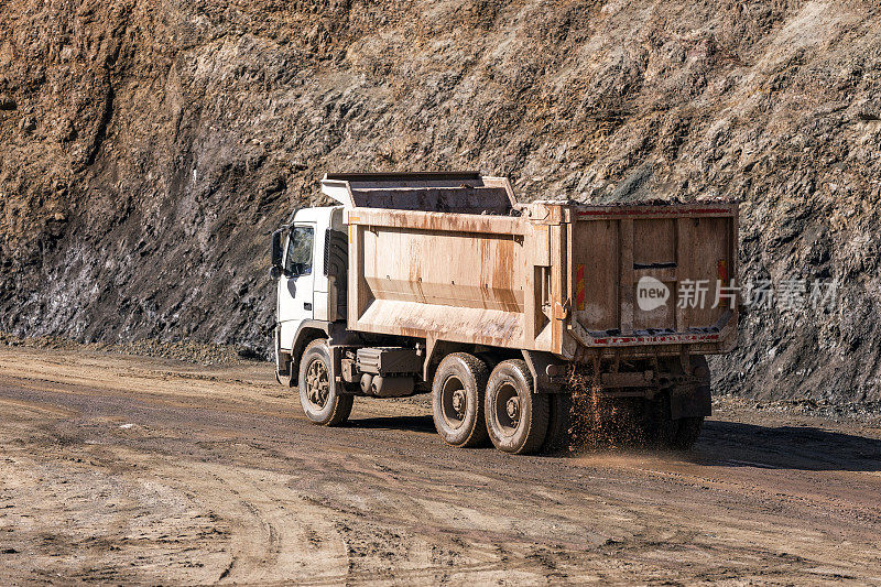 自卸卡车正开往建筑工地。一辆自卸卡车，也被称为一个翻斗卡车或自卸卡车是用来运输松散的材料(如沙子，砾石，或拆除废物)用于建筑。