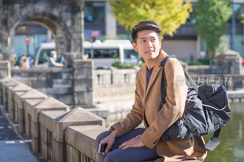 年轻的亚洲男子和日本朋友寻找旅游地点使用手机和花时间在亚洲旅行