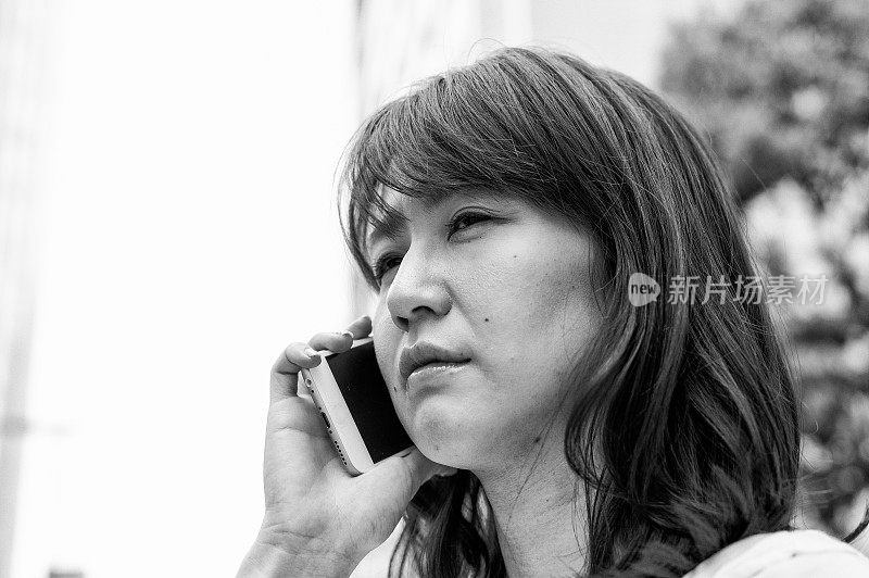 沉思的亚洲女商人上班时用智能手机聊天的肖像