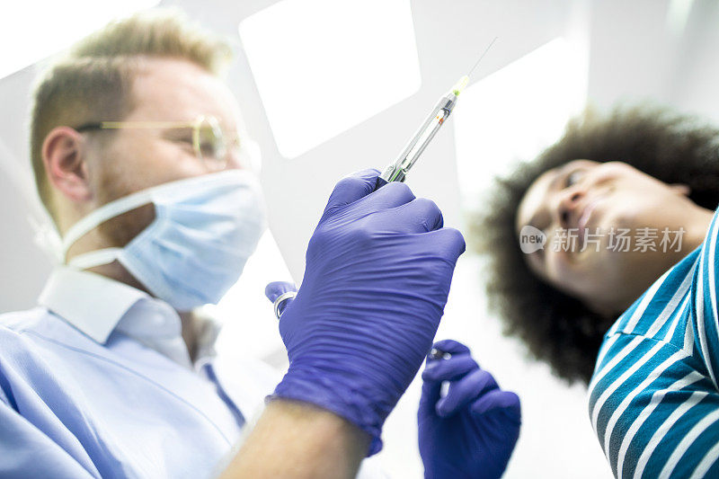 牙医用注射器和口镜给病人进行局部牙齿麻醉