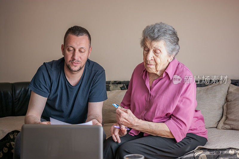 成年的孙子帮助祖母使用电脑。