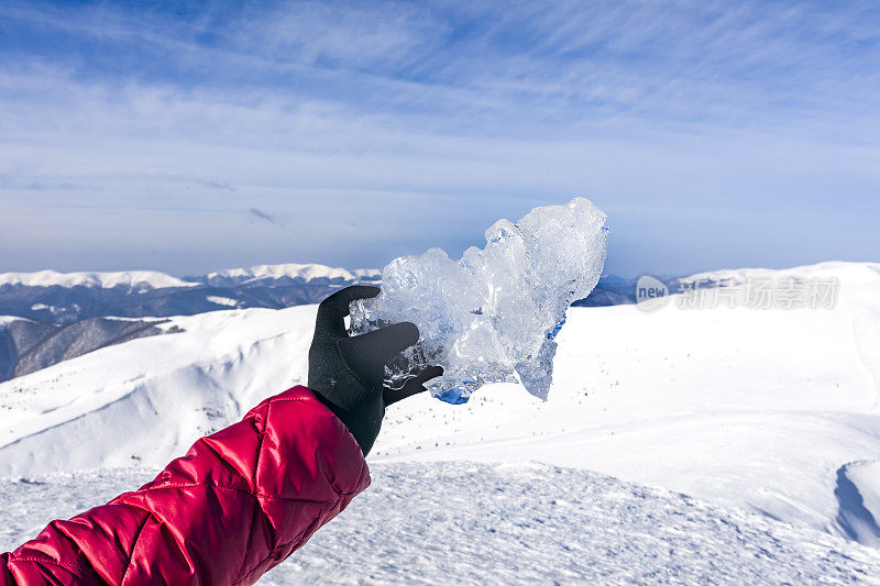 女子手持喀尔巴阡山脉上的一块冰为背景
