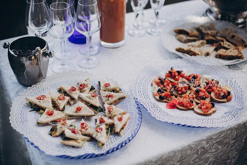 美味的意大利开胃菜在餐桌上的婚礼招待会户外。鱼子酱，海鲜，点心，香槟和酒杯在餐桌上的婚礼或圣诞宴会。豪华餐饮在户外