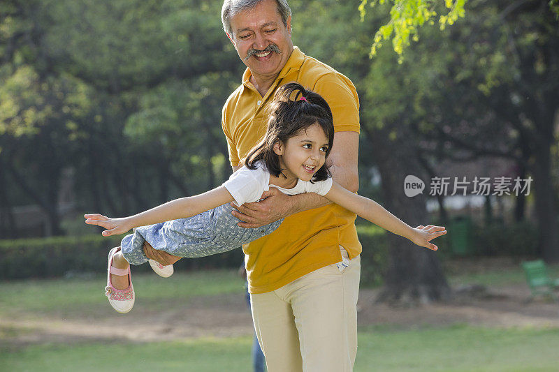 爷爷和孙女在公园里玩耍的照片