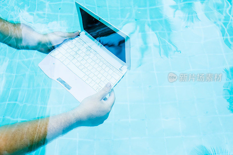 男性的手和一个笔记本电脑在水下工作。阻碍的概念在工作中。模糊抽象的背景
