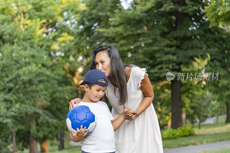 妈妈和儿子在公园里踢足球