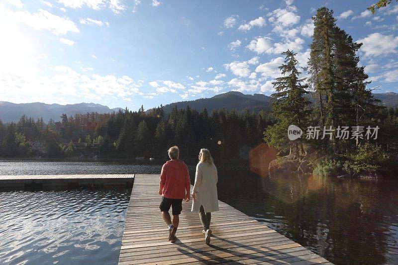 一对夫妇沿着湖边的码头散步