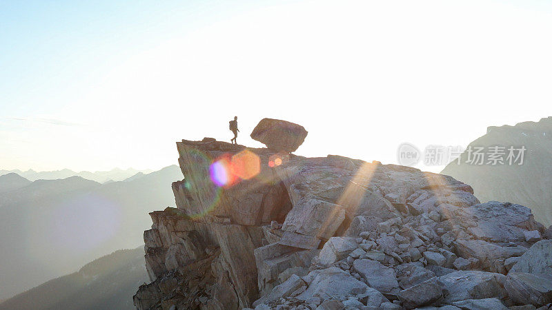 登山运动员在日出时穿过顶峰山脊