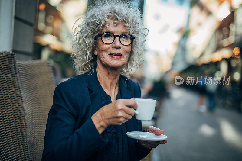 在户外咖啡厅喝咖啡的成熟女人