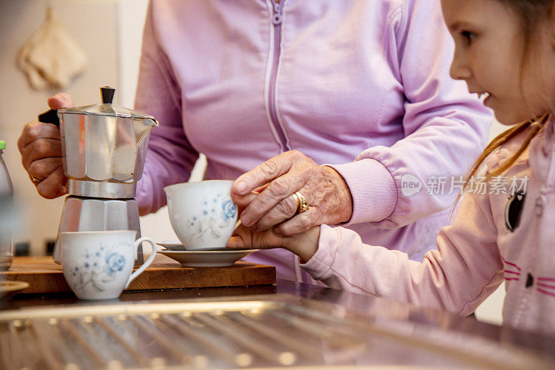 孙女帮奶奶在咖啡杯里倒咖啡