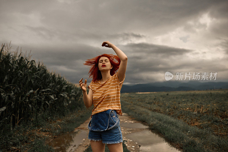 红发女郎在暴风雨的背景下摆姿势