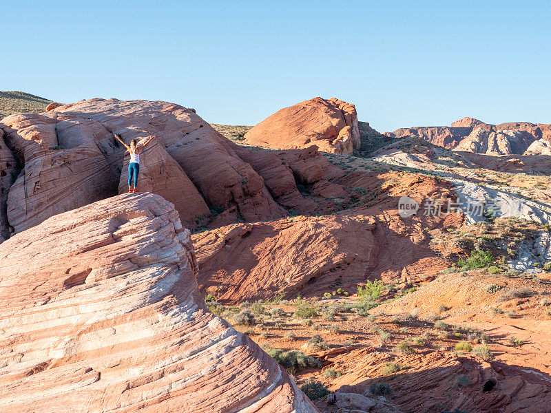 一个徒步旅行者在红砂岩上张开双臂