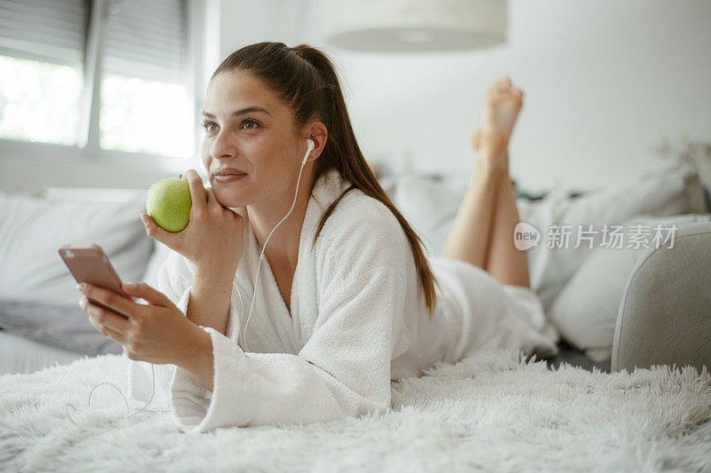 年轻漂亮的女人发短信上网在家里的沙发上。库存图片