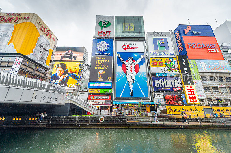 在日本大阪的道顿堀，五颜六色的广告牌照亮了大阪夜市周围的商店和零售店