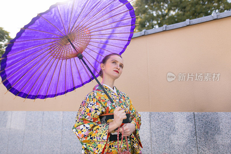 穿着和服的年轻白人妇女走在传统的日本街道上