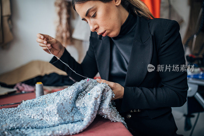 女时装设计师在她的车间里缝纫