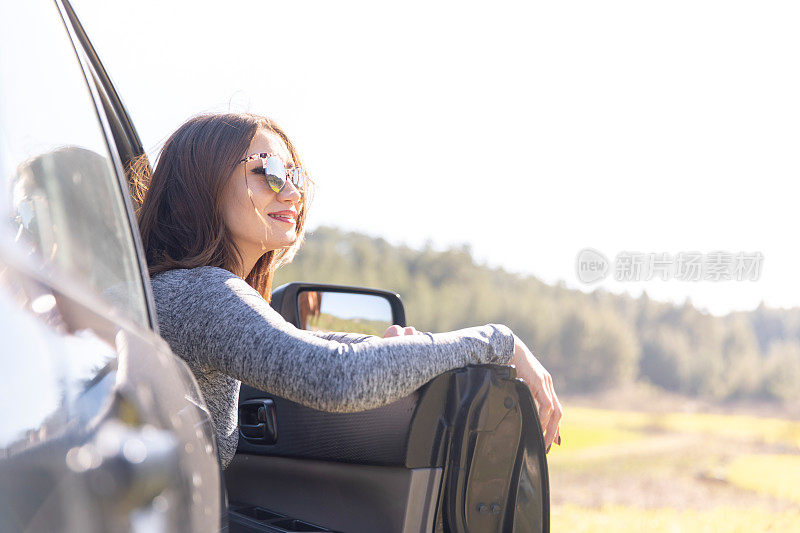 女人从打开的车门和呼吸的公路上看自然