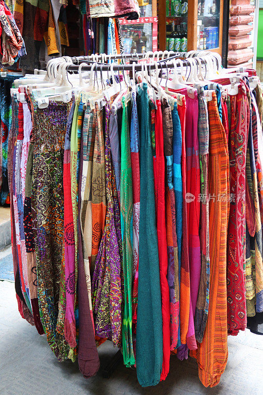 户外市场摊位展示的民族嬉皮风格的服装挂衣架，裤子和裙子