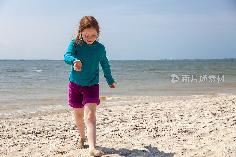 小女孩在沙滩上奔跑和玩耍