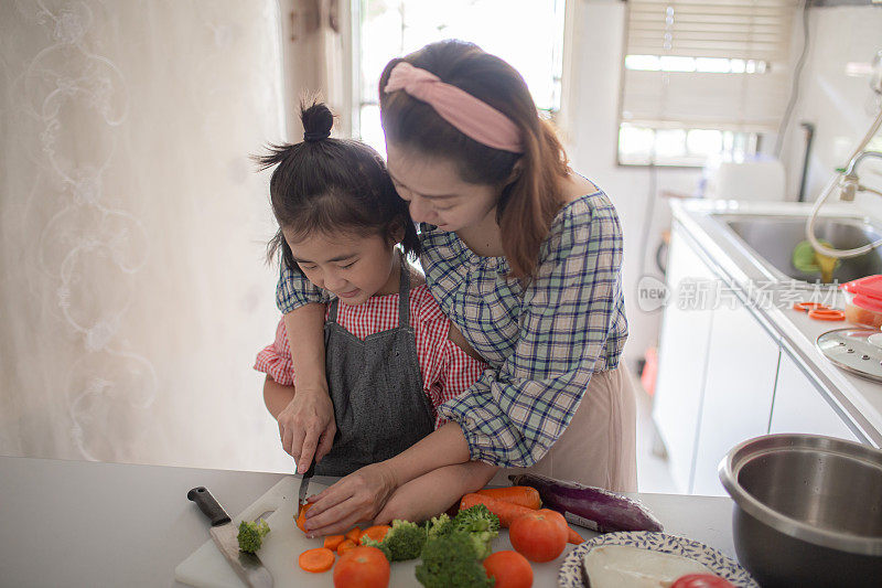 亚洲华人母亲准备食物在厨房柜台与她的女儿