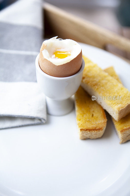 半熟的煮鸡蛋和士兵在一个白色的盘子里有拷贝空间