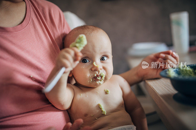 年轻的母亲试图用勺子喂小男孩