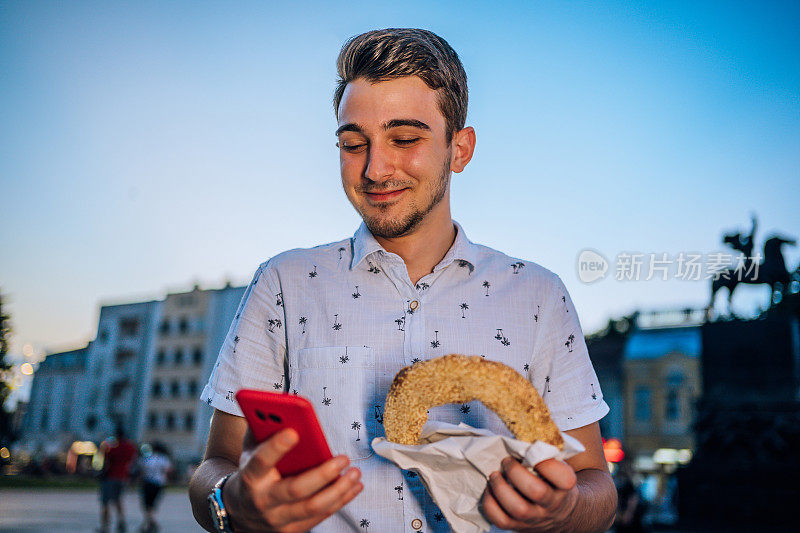 年轻人一边用手机一边吃百吉饼