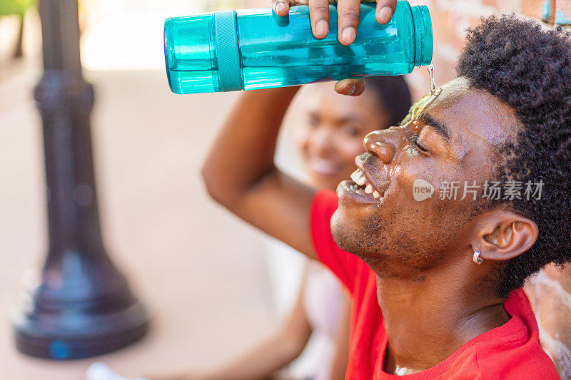 千禧年男性和Z一代女性在炎热的夏日里锻炼，拿着水瓶补水