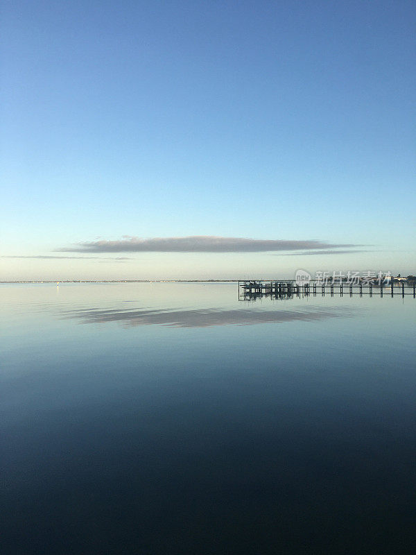 平静的黎明，有码头的近岸内水域，映照出一片低矮的云块