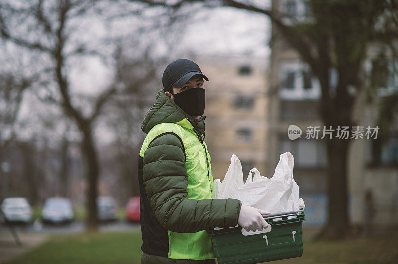 年轻的送货员戴着防护面具和防护手套