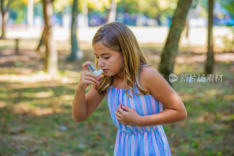 一个可爱的女孩在公园里使用哮喘吸入器。