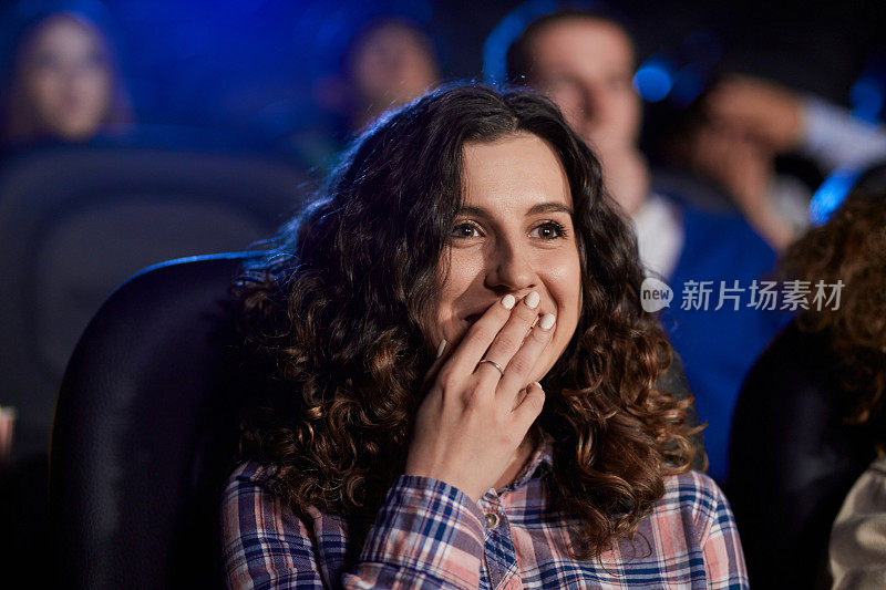 年轻笑着的女孩在电影院看喜剧。