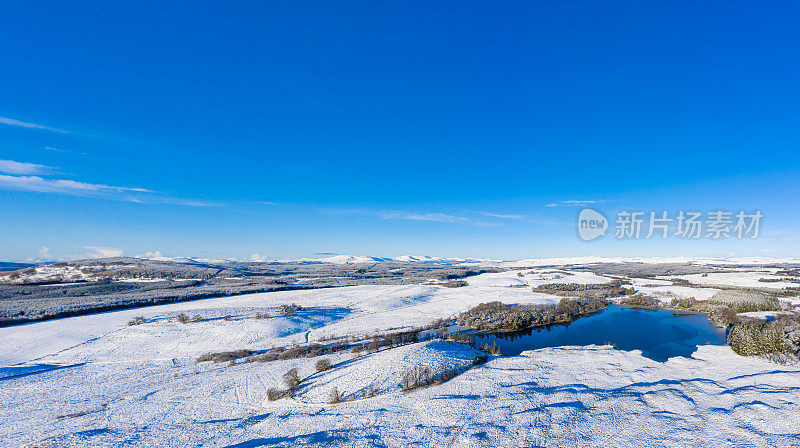 这是苏格兰西南部一个偏远的小湖的高角度全景，上面覆盖着雪