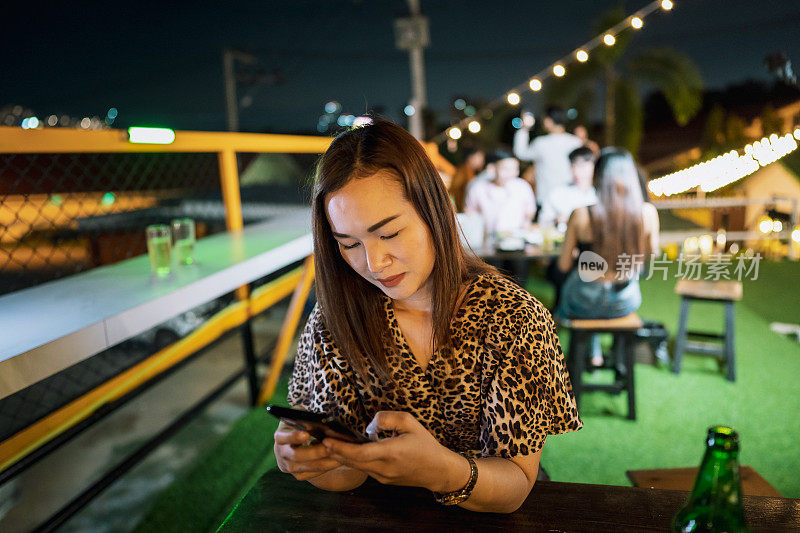 独自坐在户外餐厅喝啤酒的女人