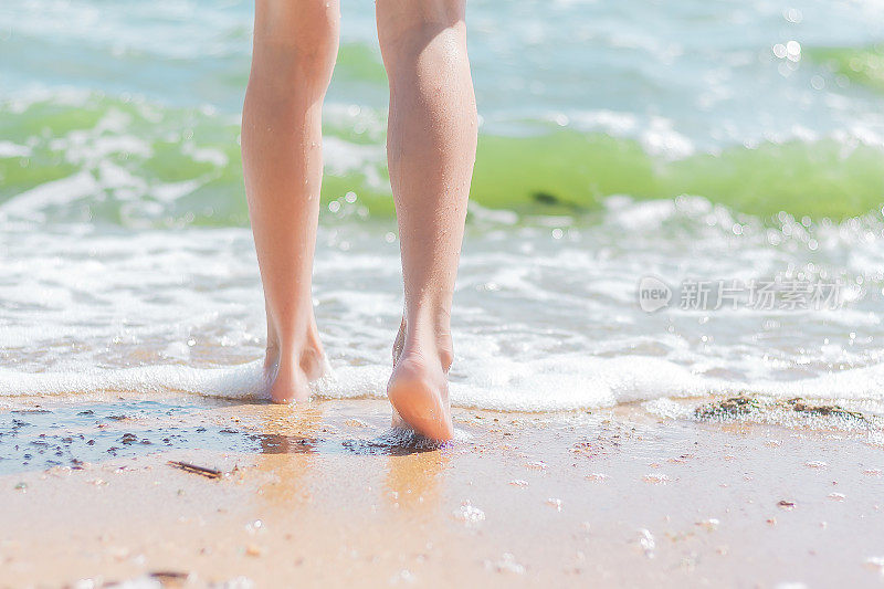 一个女孩光着脚在沙滩上走到海水里。