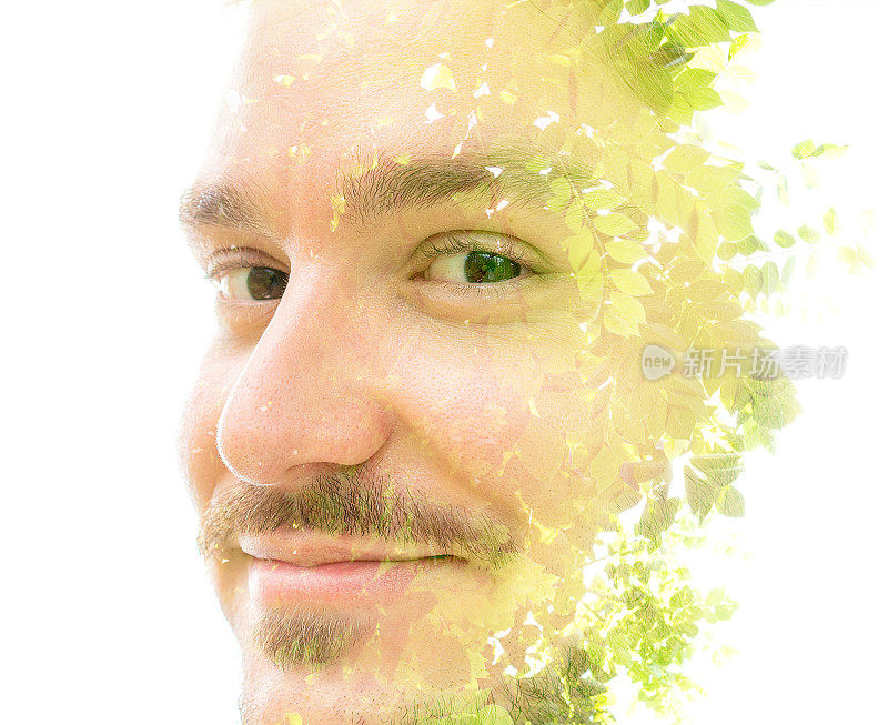 一个微笑的男人的双重曝光肖像与绿色的树叶合上了