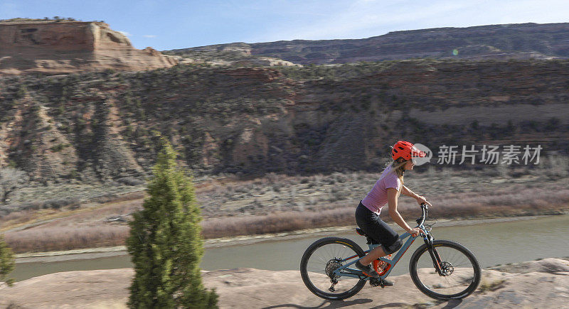 女性山地自行车在早上遵循沙漠路径