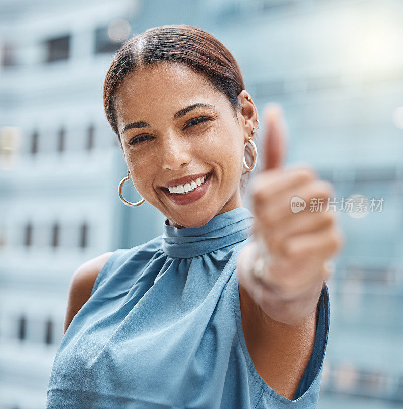 一个年轻的女商人在城市背景下竖起大拇指的照片