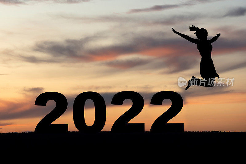 一个女人的剪影在2022年的日落在山上跳