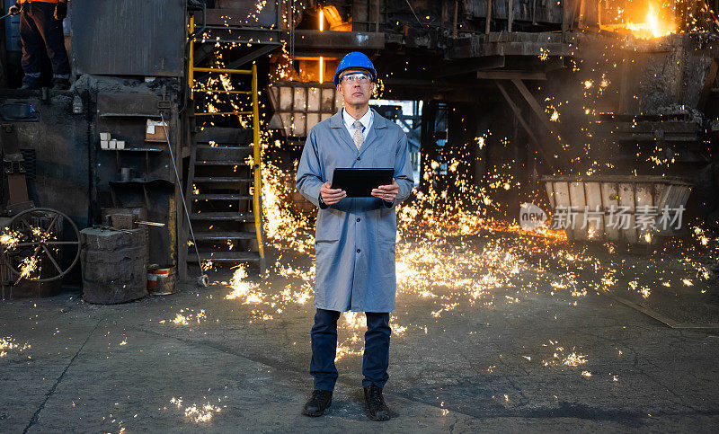 钢铁厂男工程师在铸造厂使用平板电脑。工业环境