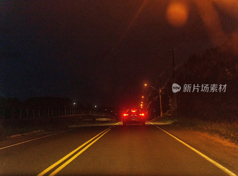 汽车夜间行驶在黑暗的双车道公路上