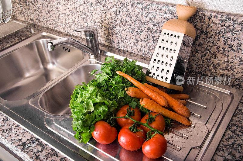 用不锈钢水槽清洗厨房柜台上的蔬菜