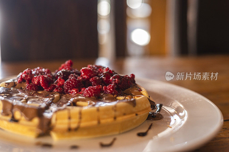 美味的华夫饼覆盖在巧克力和浆果低角度视图在一个乡村的桌子上