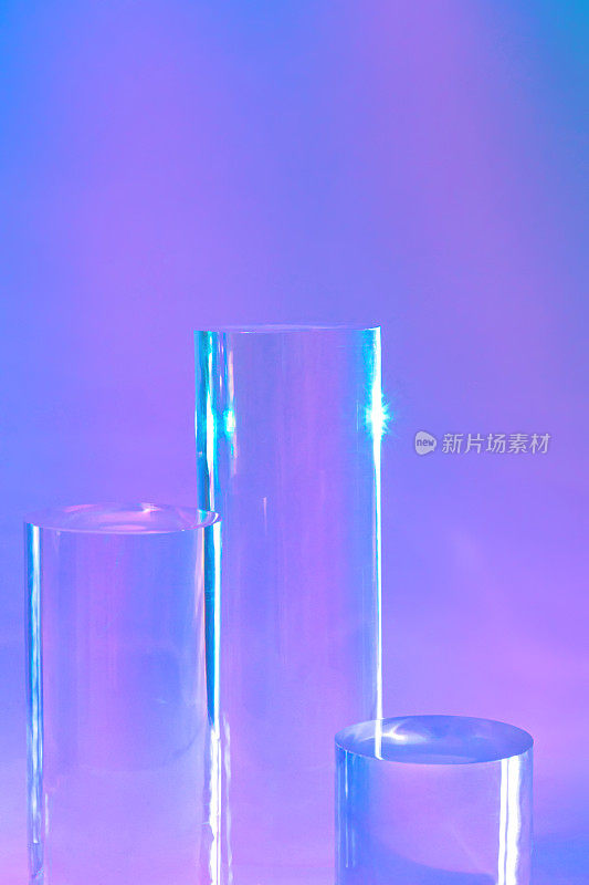全息霓虹灯背景上的三个透明玻璃圆筒平台